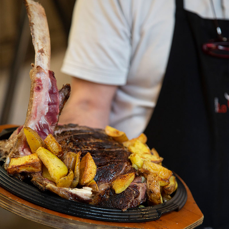  Cameriere che tiene in mano un piatto con patate e carne 